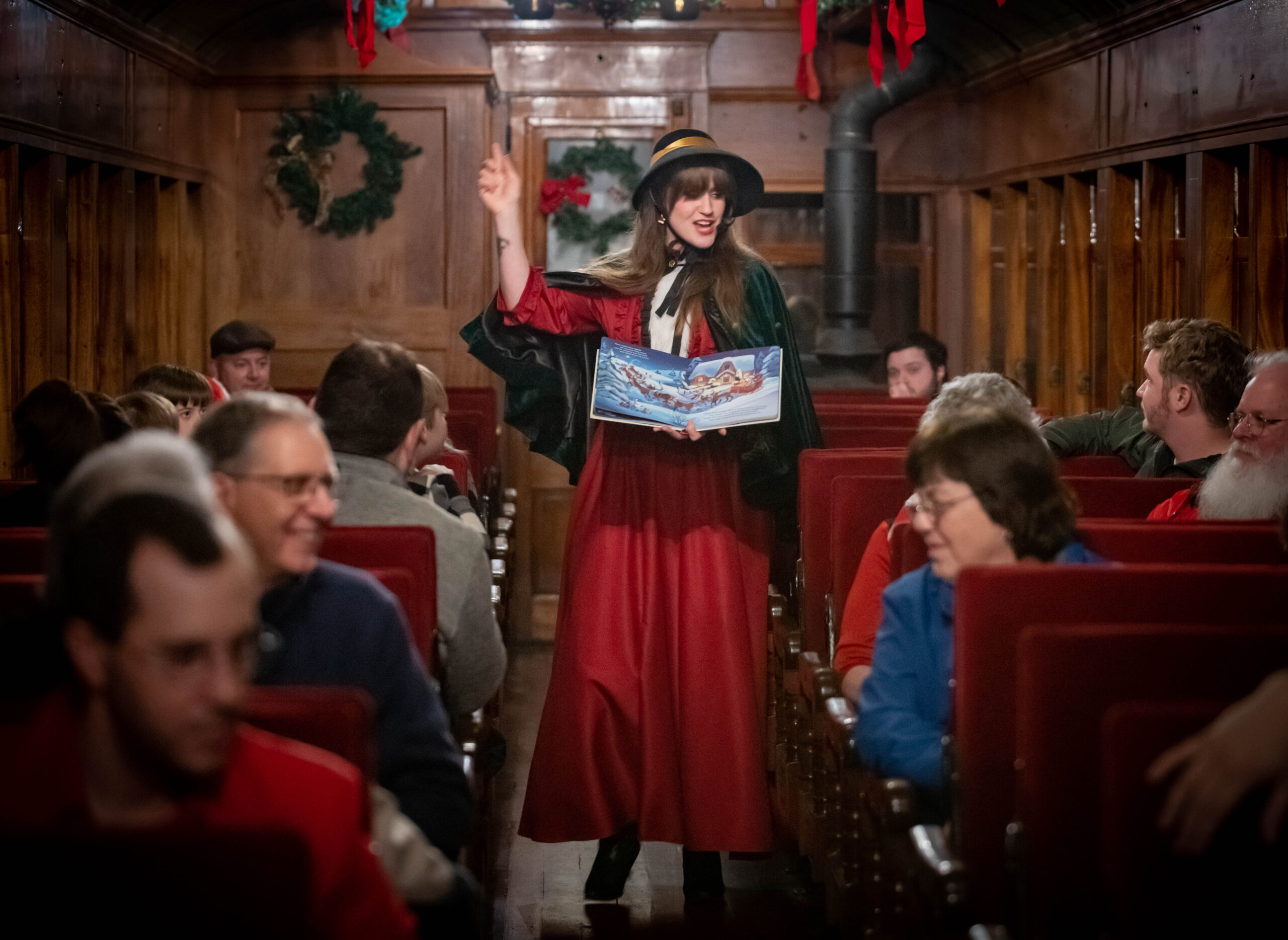 People on a train gather to hear a costumed actress read The Night Before Christmas.