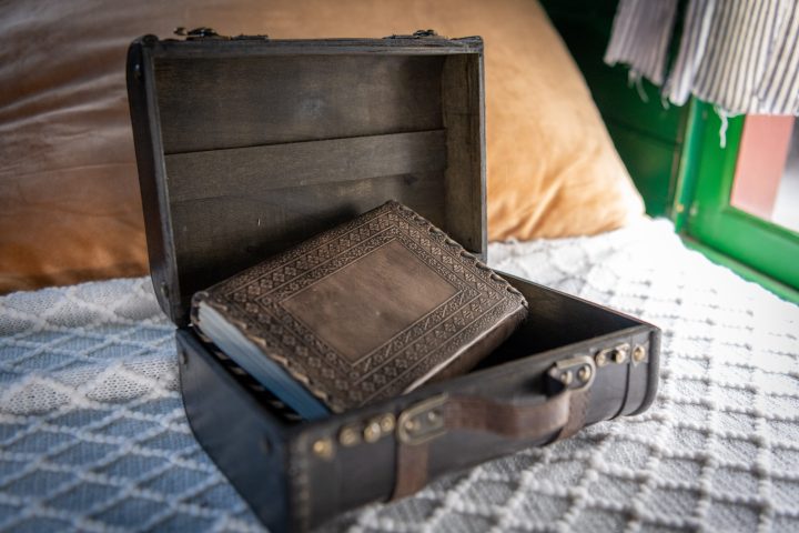 A briefcase open on a bed, with a book inside.