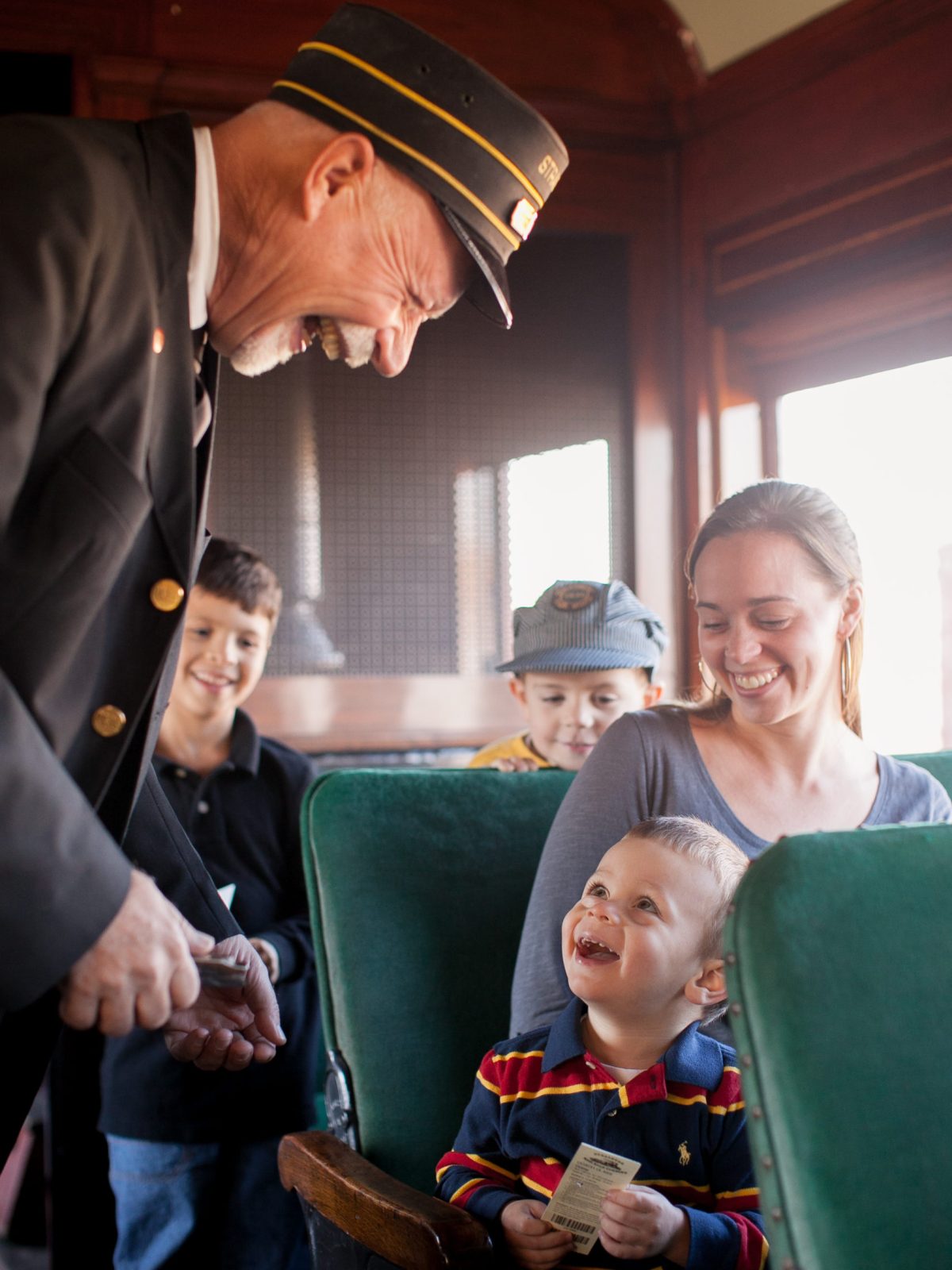 039_StrasburgRRTennison A smiling train conductor reaches down to take the train ticket from the little boy.