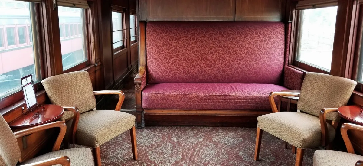 The Elegant Express: Valentine’s Day – The President’s Car Image 2 Cushioned chairs and a bench inside the president's car of the Strasburg Rail Road.