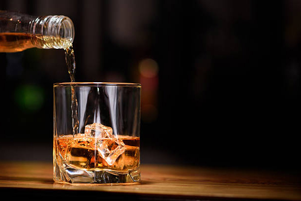 A bottle of whiskey being poured into a glass.