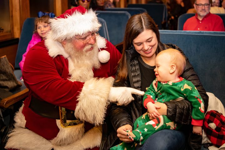 Santa visiting a child who is being held by his mother.