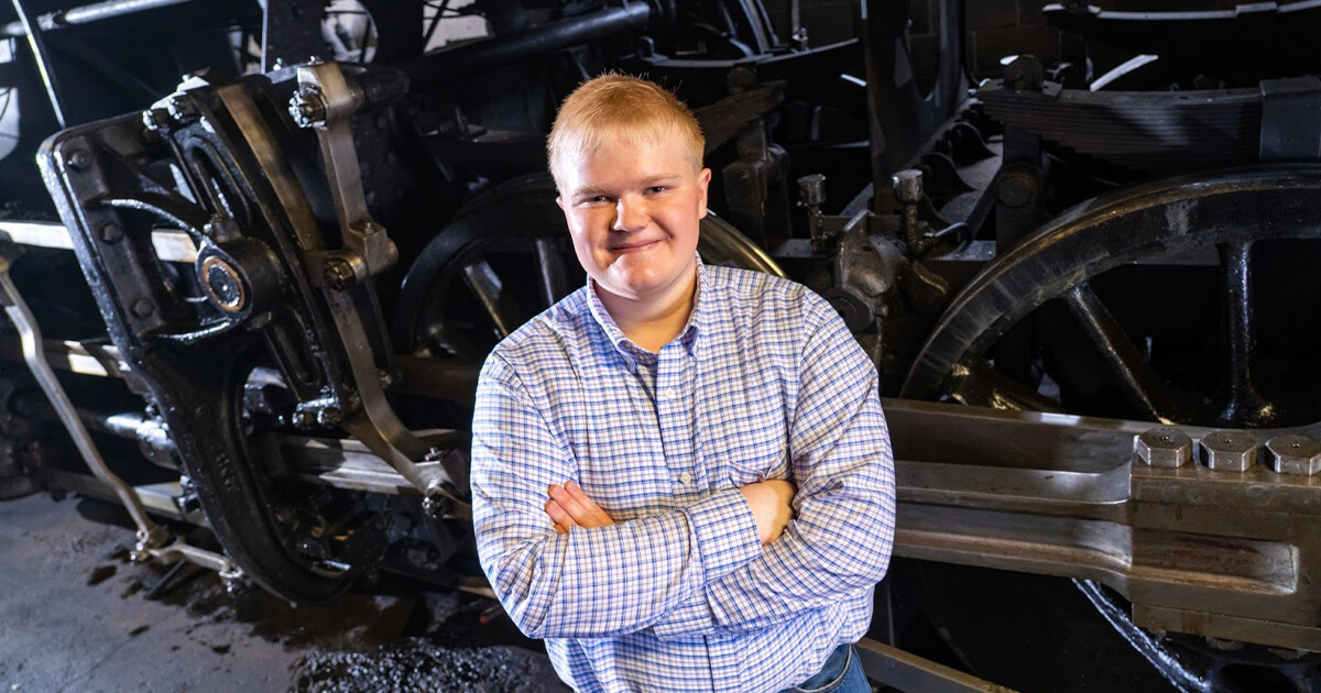 A boy standing near a train for his senior portrait photo at Strasburg Rail Road.
