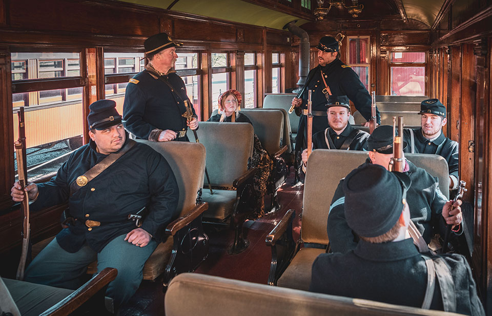 A group of people in uniform sitting on a train.