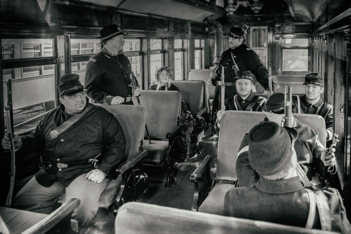 A group of people in uniform, sitting on a train.