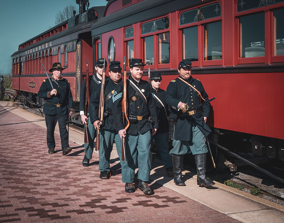 A group of soldiers in uniform standing next to a train.
