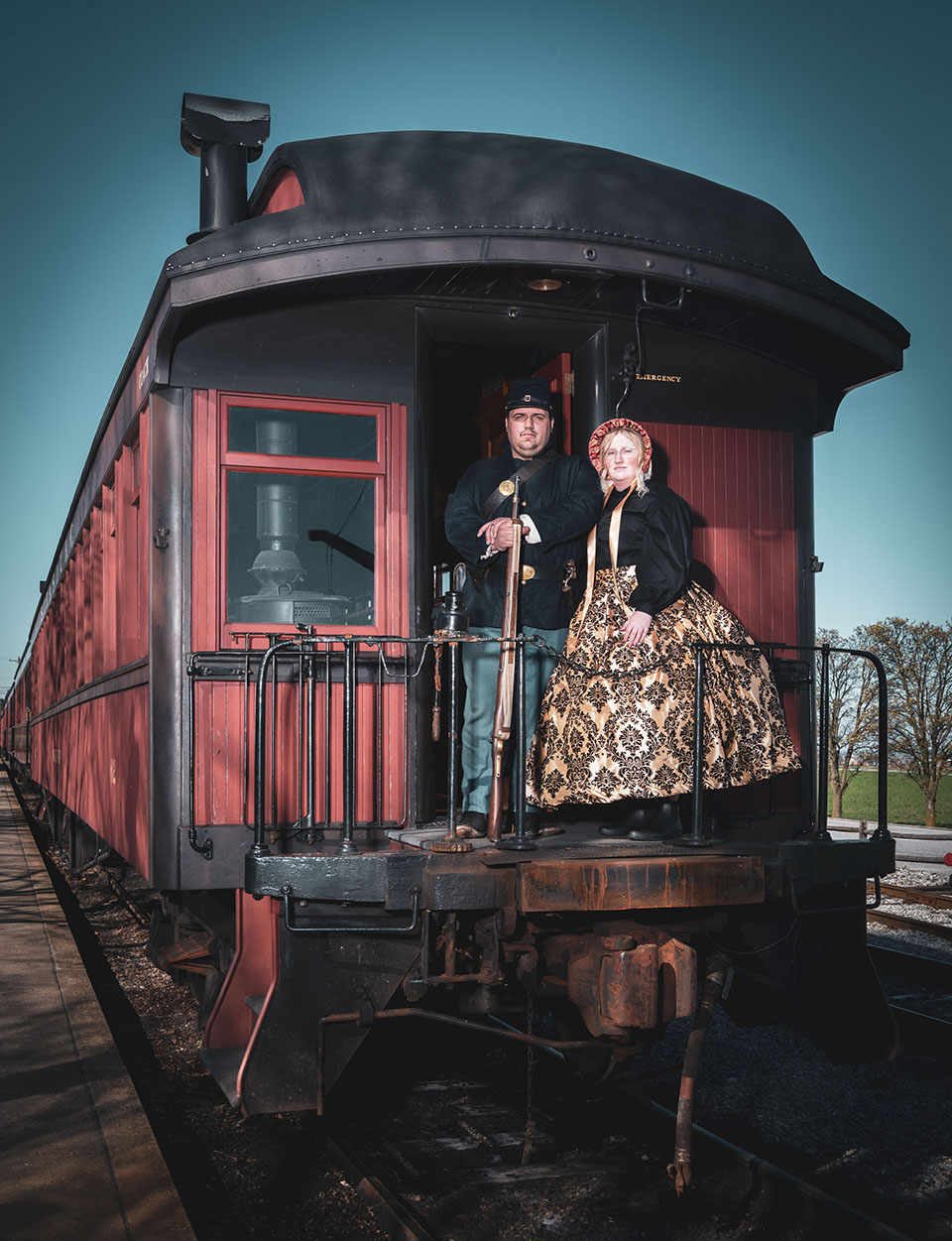 Two people standing outside on a balcony of a train car.