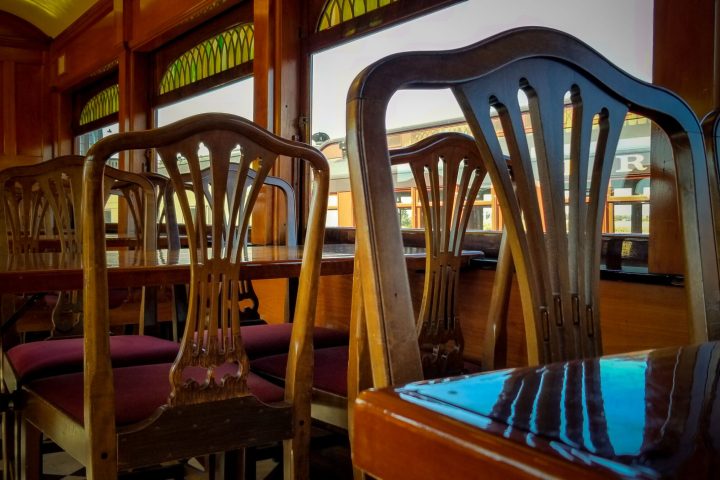 Hardwood chairs at a table on a dining train.