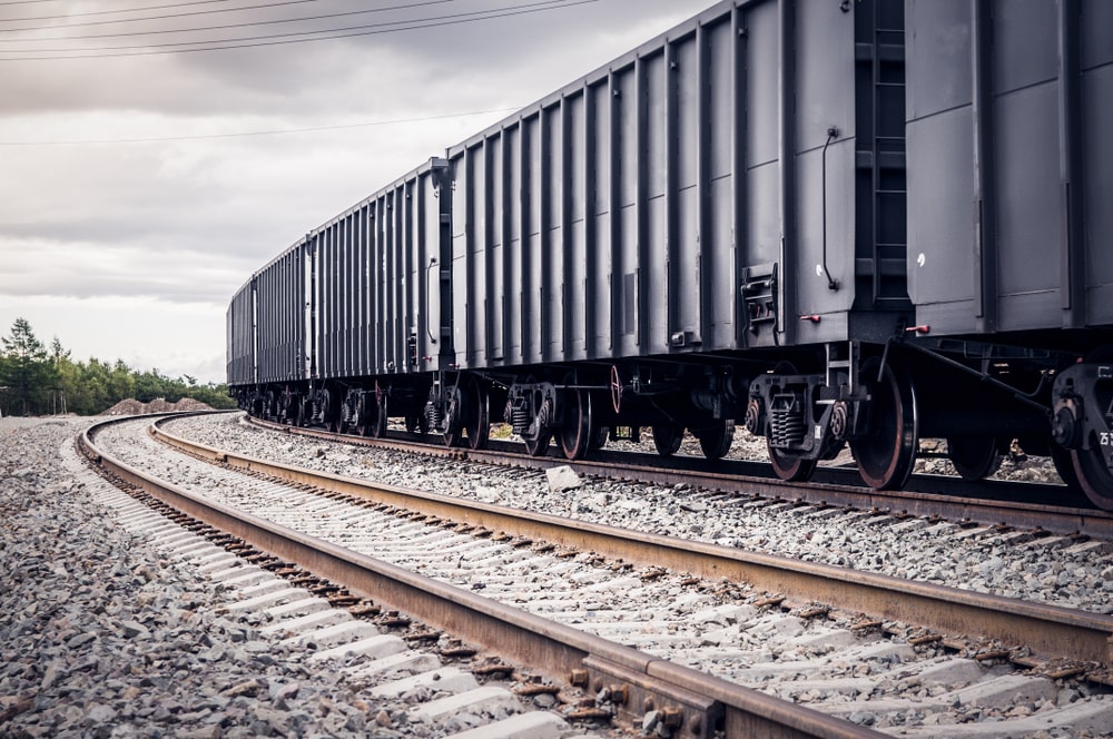 Rail freight cars traveling on tracks outdoors.