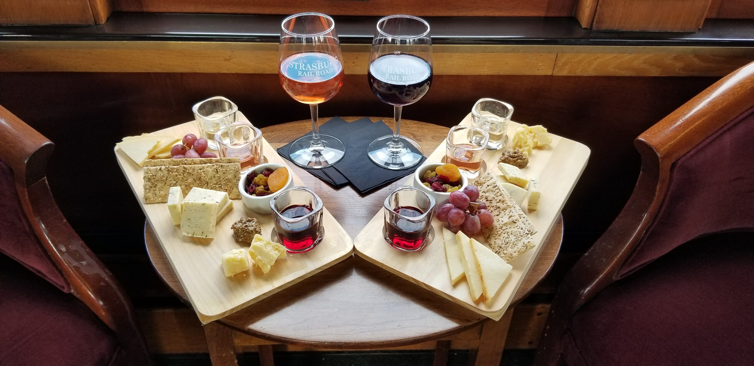 Two cheese boards and half-filled wine glasses sitting on a round table.