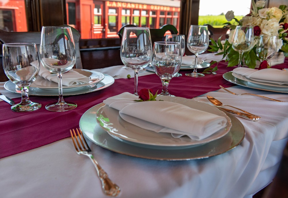 A dining table with wine glasses and plates inside a dining train car.