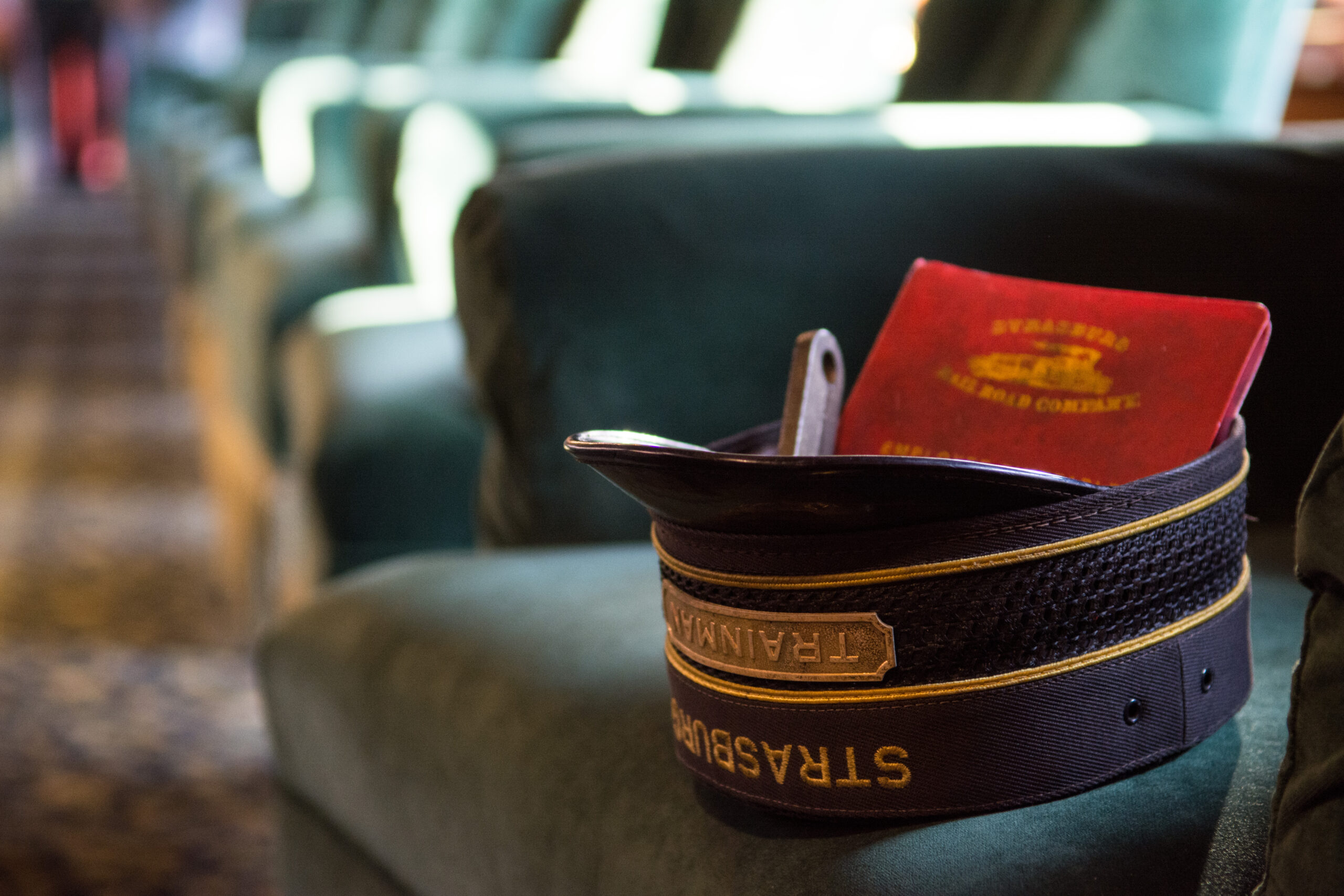 An upside-down conductor's hat sitting on a train passenger seat.