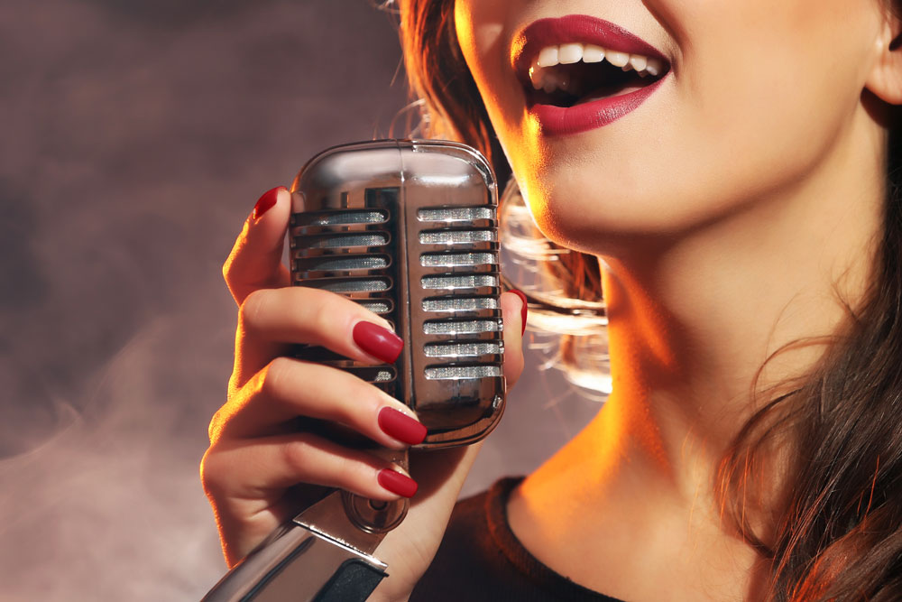 A close-up of a woman singing into a microphone.